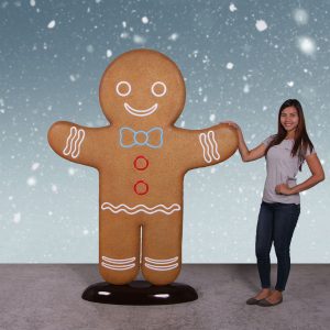 Girl standing beside giant gingerbread man decoration