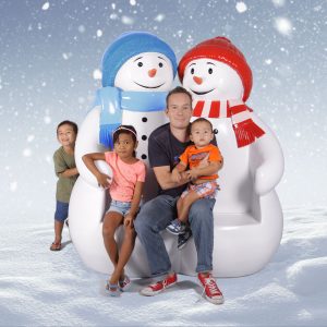 Family sitting on giant snowman bench